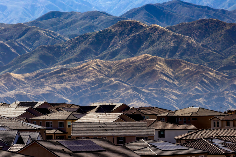 Rows of suburban rooftops with hills in the background