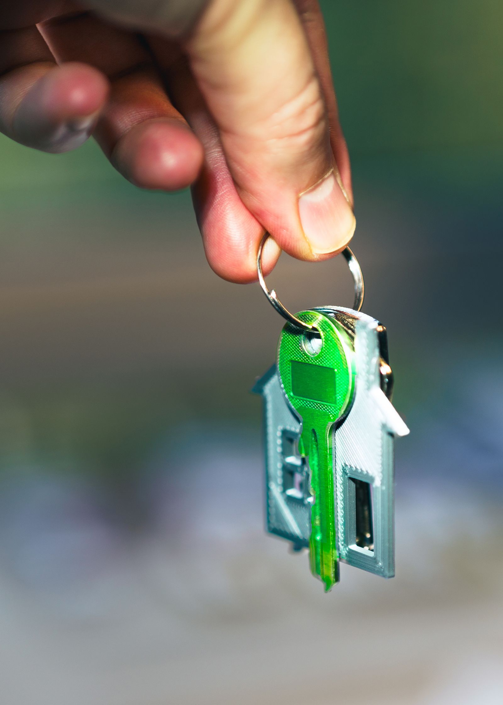Hand holding a house-shaped keychain in sunlight
